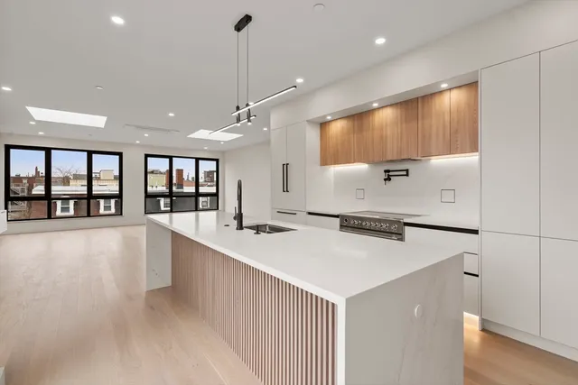 a large kitchen with stainless steel appliances a large counter top a stove and a refrigerator