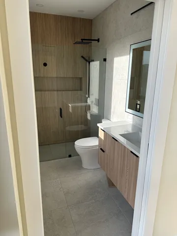 a bathroom with a granite countertop sink a toilet and shower