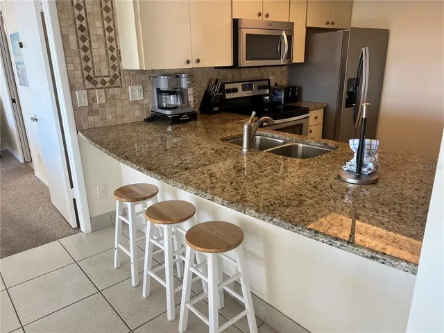 a kitchen with stainless steel appliances granite countertop a sink and a refrigerator