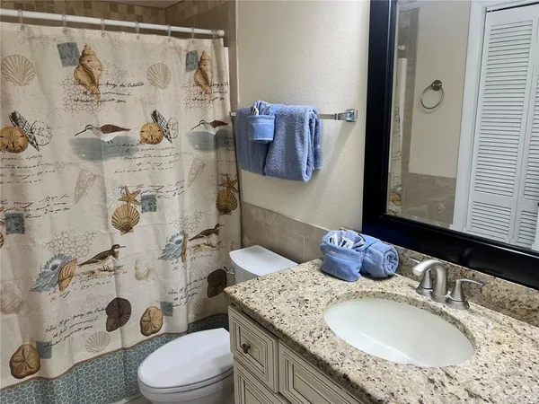 a bathroom with a granite countertop sink a toilet and shower curtain