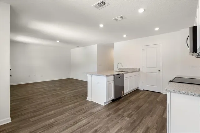 a view of kitchen with granite countertop cabinets and refrigerator