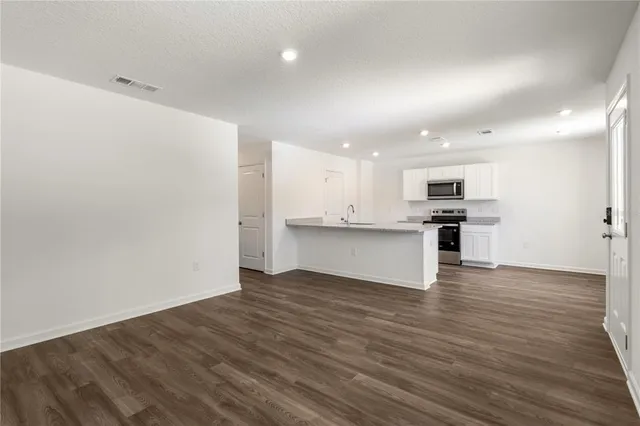 an open kitchen with white cabinets and wooden floor