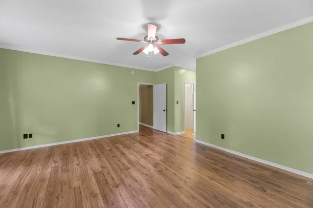 a view of an empty room with window and wooden floor