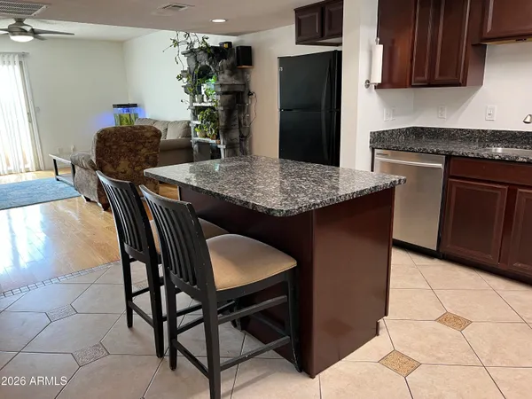 a kitchen with stainless steel appliances granite countertop a table chairs in it and wooden floors