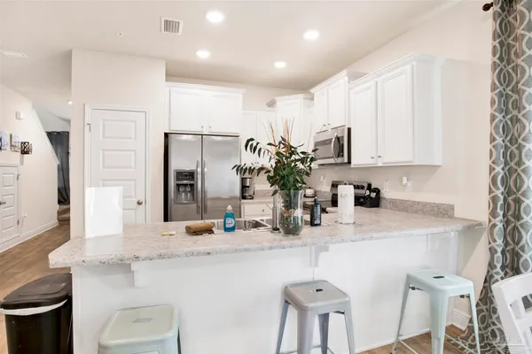 a kitchen with kitchen island granite countertop a sink and white cabinets