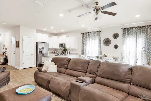 a living room with furniture kitchen area and a chandelier