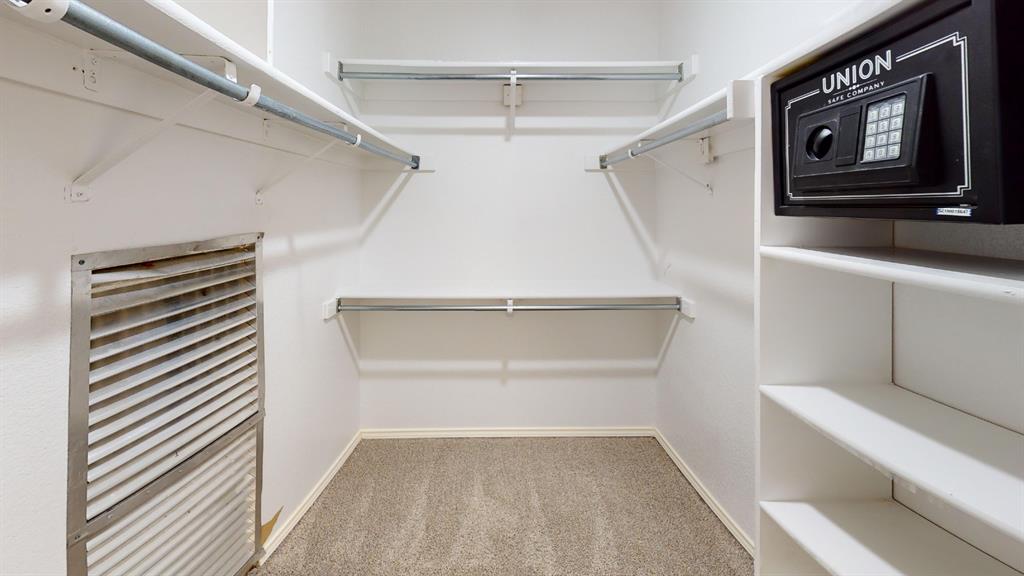 7913 Rice Drive Rowlett, TX 75088 - Photo 21 of 25 Walk-in closet featuring carpet flooring, built-in shelving, hanging rods, and a wall-mounted safe
