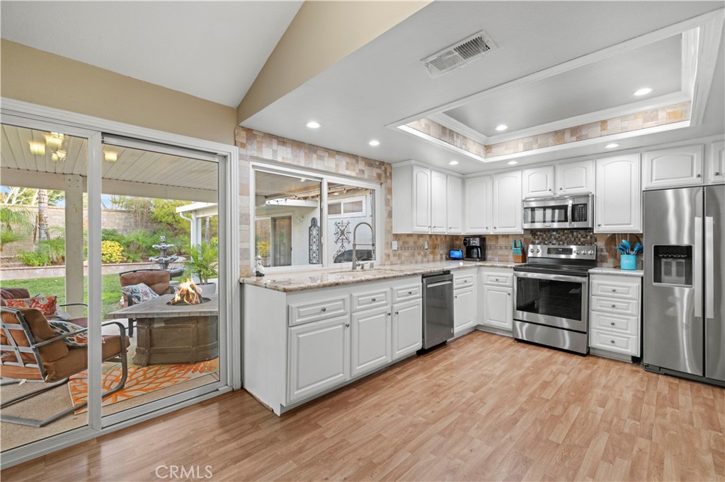 23716 Rotunda Road Valencia, CA 91355 - Photo 15 of 39 a kitchen with stainless steel appliances granite countertop a stove top oven a sink dishwasher a refrigerator and white cabinets with wooden floor