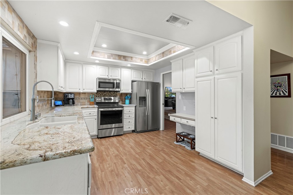 23716 Rotunda Road Valencia, CA 91355 - Photo 16 of 39 a kitchen with granite countertop a refrigerator and a stove top oven
