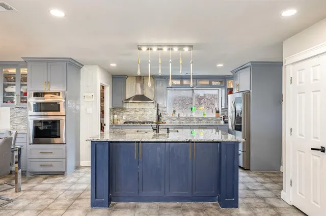 a kitchen with stainless steel appliances granite countertop a refrigerator and a stove