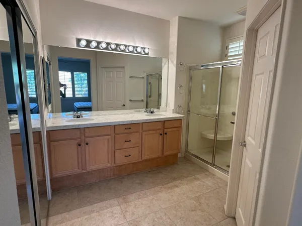 a spacious bathroom with a double vanity sink a mirror and a shower