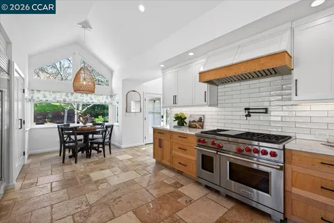 a kitchen with stainless steel appliances a stove a sink and a dining table
