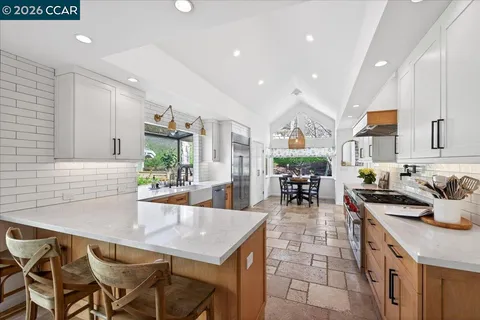 a kitchen with stainless steel appliances granite countertop a stove a sink a dining table and chairs