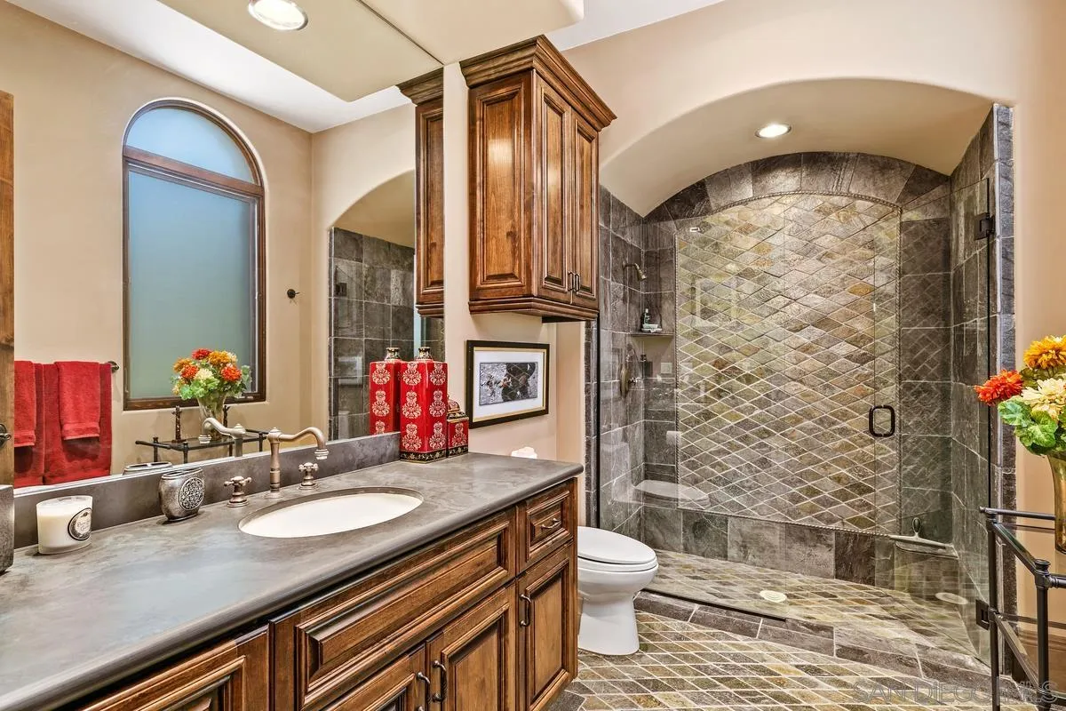 6934 St Andrews Road Rancho Santa Fe, CA 92067 - Photo 30 of 49 a bathroom with a granite countertop sink a toilet a mirror and shower