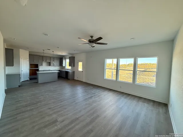 a view of a kitchen with a stove cabinets a ceiling fan and wooden floor