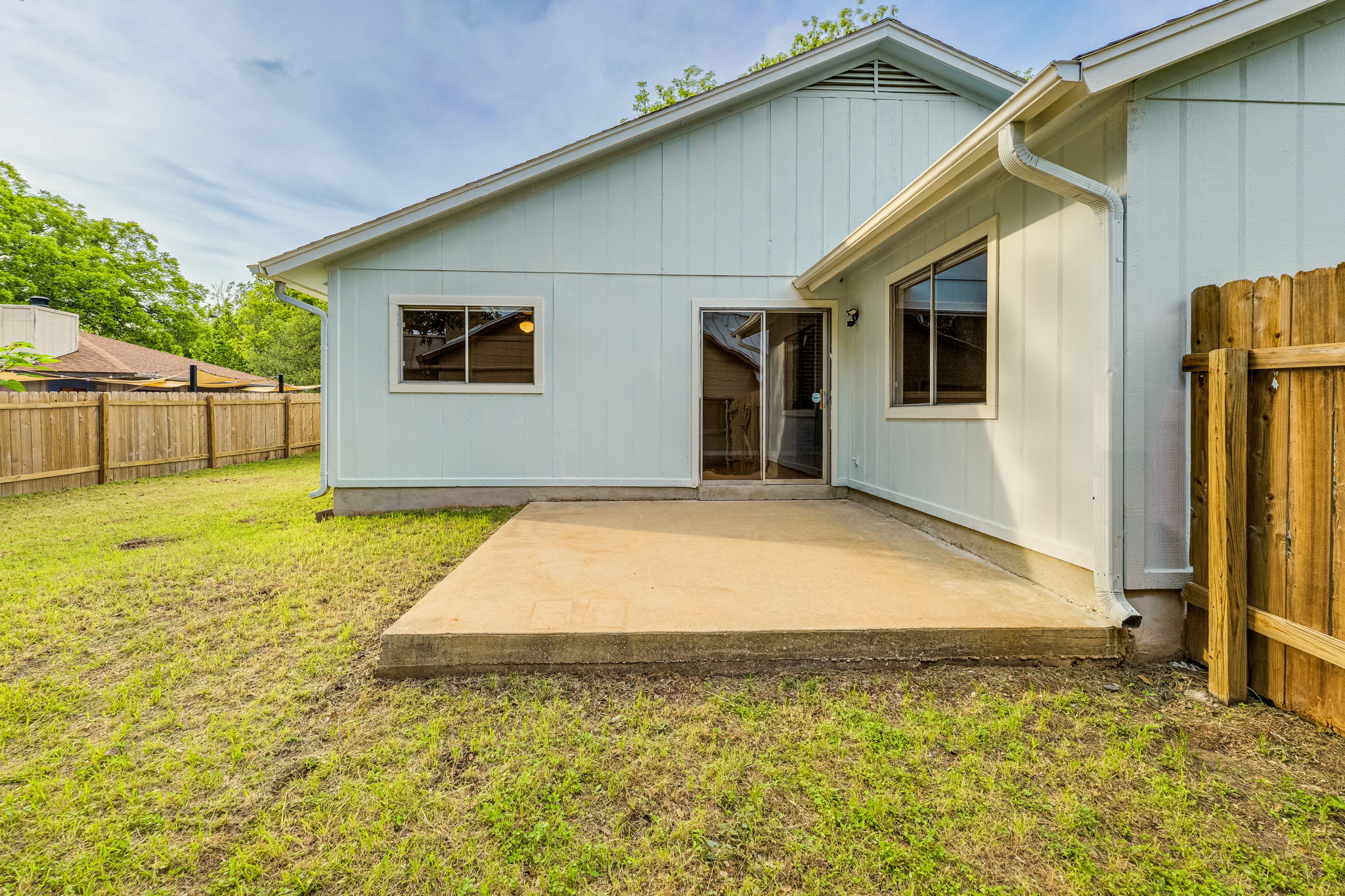 4815 Transit Circle Austin, TX 78727 - Photo 30 of 35 Backyard patio area featuring a spacious concrete slab, sliding glass door entry, multiple windows for great natural light, light-colored siding, and a wood privacy fence for added privacy and comfort.