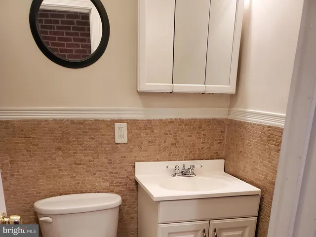 a bathroom with a toilet sink vanity and mirror