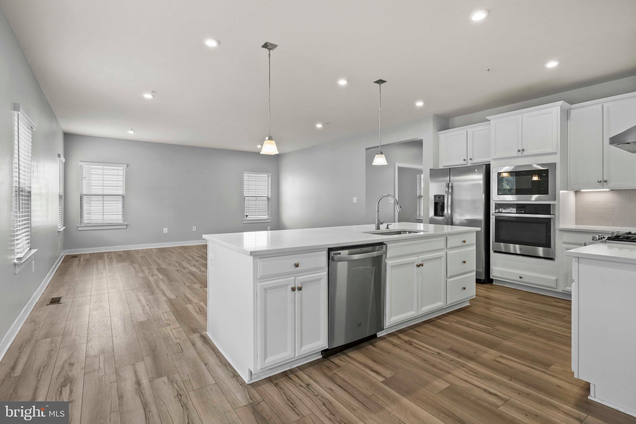 3903 Emory Ridge Road Brandywine, MD 20613 - Photo 3 of 42 a large kitchen with kitchen island a sink dishwasher a refrigerator and white cabinets with wooden floor
