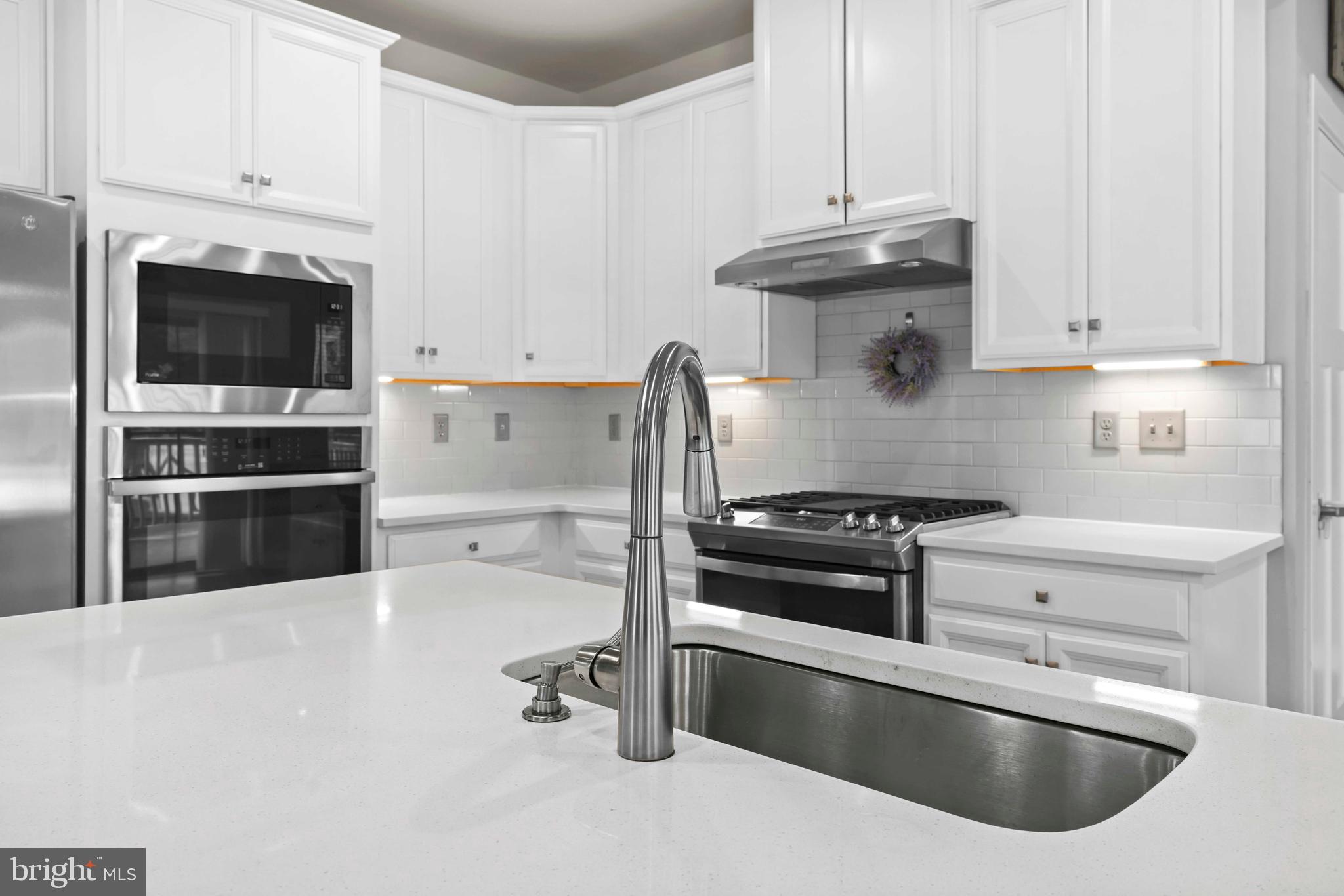 3903 Emory Ridge Road Brandywine, MD 20613 - Photo 5 of 42 a kitchen with granite countertop a sink stainless steel appliances and white cabinets