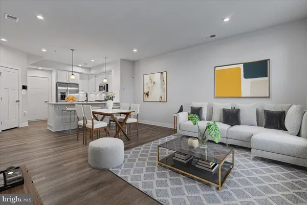 a living room with couches and kitchen view with wooden floor