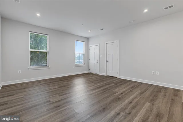 an empty room with wooden floor and windows