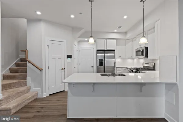 a large kitchen with stainless steel appliances kitchen island a large counter top and a refrigerator