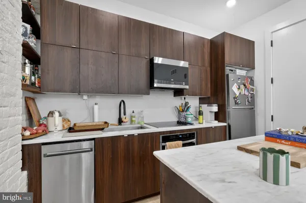 a kitchen with stainless steel appliances a sink a stove a refrigerator a sink a counter space and cabinets