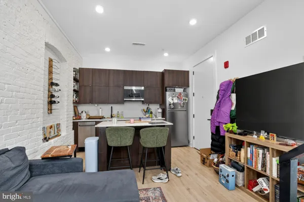a living room with stainless steel appliances furniture a rug and a flat screen tv
