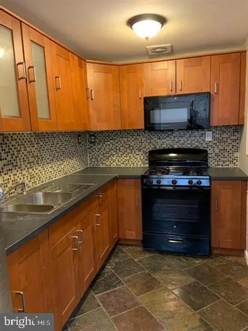 a kitchen with stainless steel appliances granite countertop a stove a sink and a microwave
