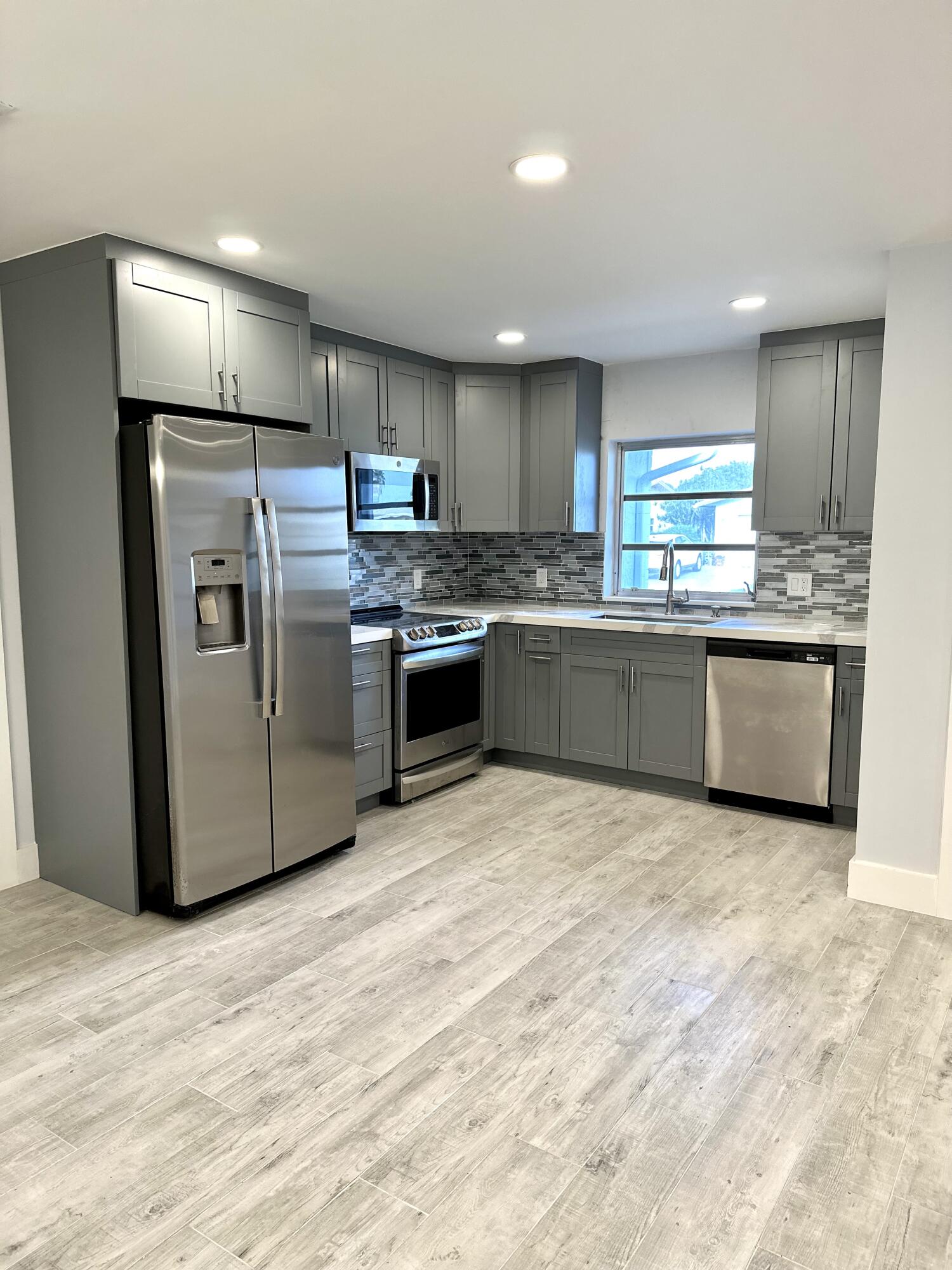 13357 Vía Vesta, Unit B Delray Beach, FL 33484 - Photo 6 of 26 a kitchen with stainless steel appliances granite countertop a refrigerator and a stove top oven