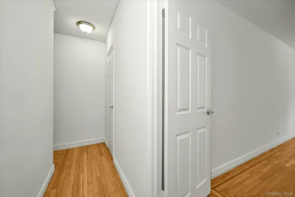 a view of a hallway with wooden floor and a bathroom
