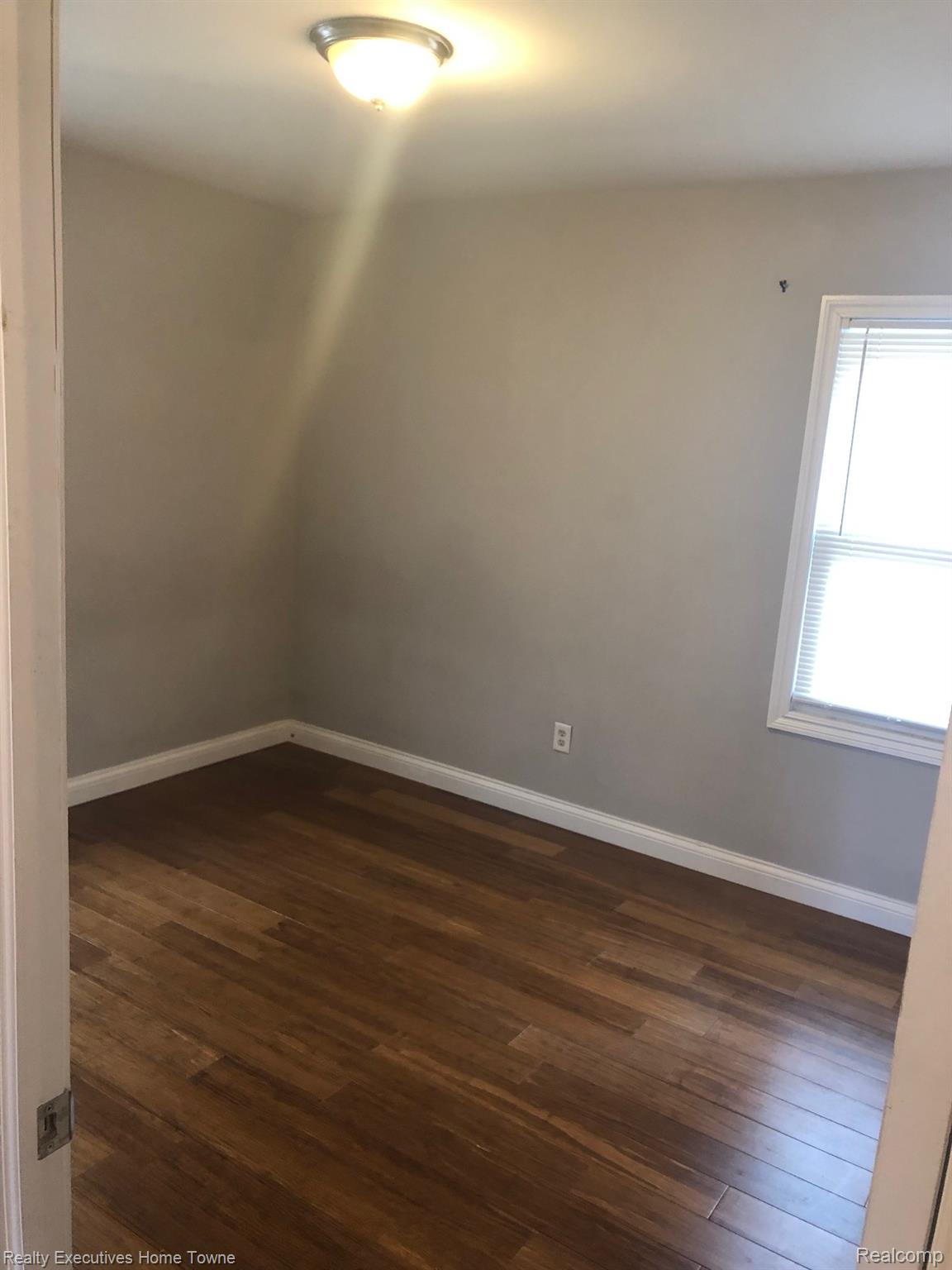 2427 Cambridge Road Berkley, MI 48072 - Photo 10 of 17 Interior room featuring wood-finish flooring, light grey walls, white trim, and a flush mount ceiling light fixture