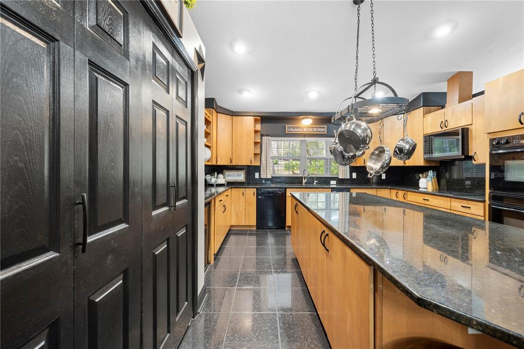 4244 Bessemer Road Brooksville, FL 34602 - Photo 14 of 56 a large kitchen with stainless steel appliances kitchen island granite countertop a sink a counter space and a view of living room
