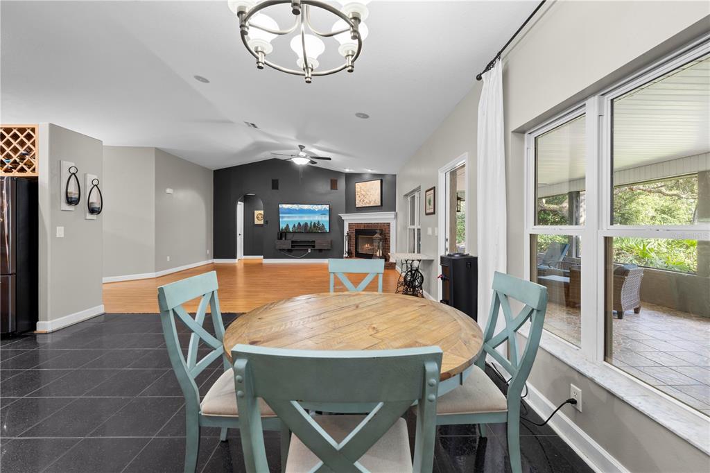 4244 Bessemer Road Brooksville, FL 34602 - Photo 22 of 56 a dining room with wooden floor a chandelier a wooden table and chairs