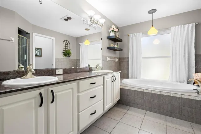 a spacious bathroom with a granite countertop sink a mirror and a bathtub