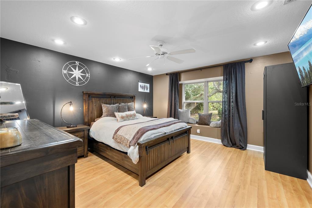 4244 Bessemer Road Brooksville, FL 34602 - Photo 34 of 56 a spacious bedroom with a bed and a dresser with wooden floor