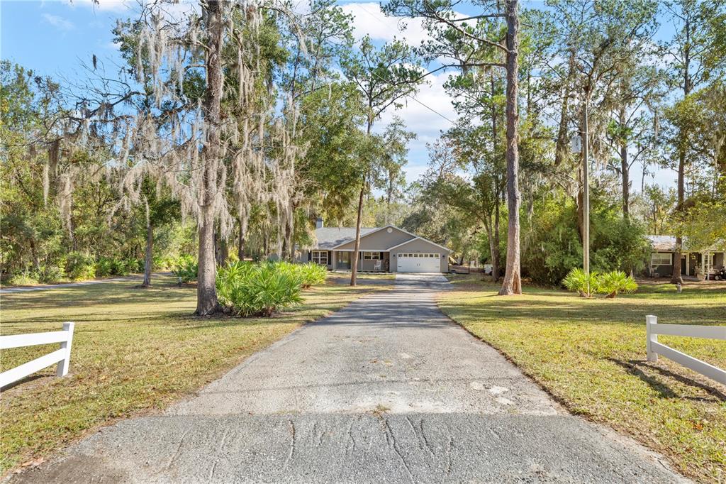 4244 Bessemer Road Brooksville, FL 34602 - Photo 56 of 56 a view of a house with a yard and large trees