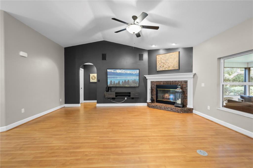 4244 Bessemer Road Brooksville, FL 34602 - Photo 6 of 56 a view of a livingroom with a fireplace a ceiling fan and windows