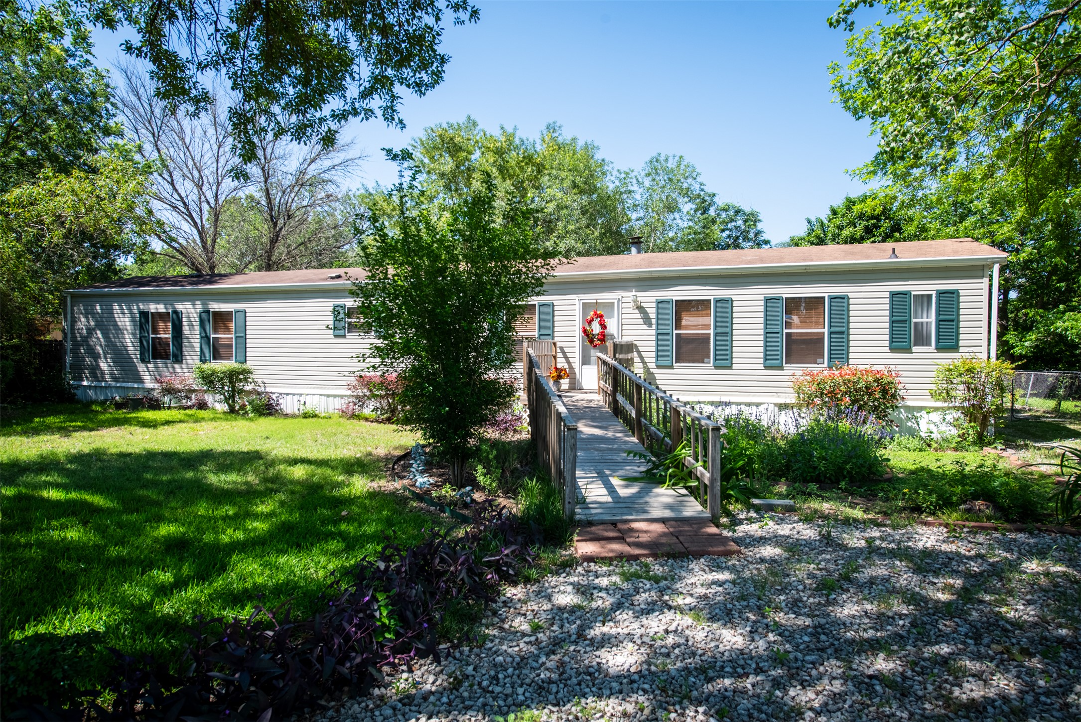 Single-story residence featuring light-colored siding, green window shutters, and a wood entry ramp