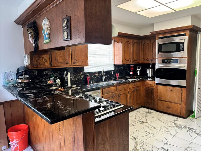 a kitchen with stainless steel appliances granite countertop a stove a sink and a microwave