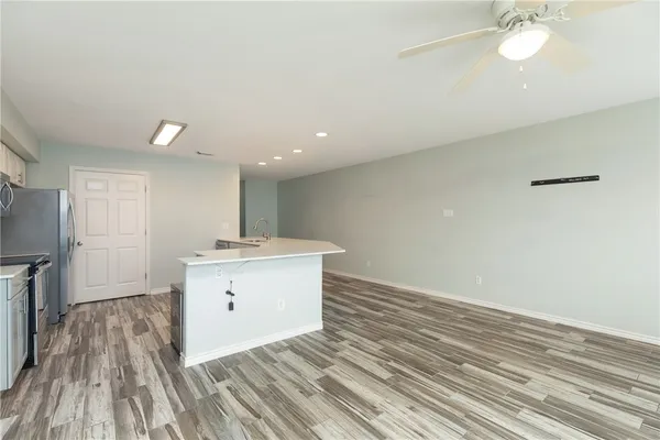 a view of kitchen and empty room with wooden floor