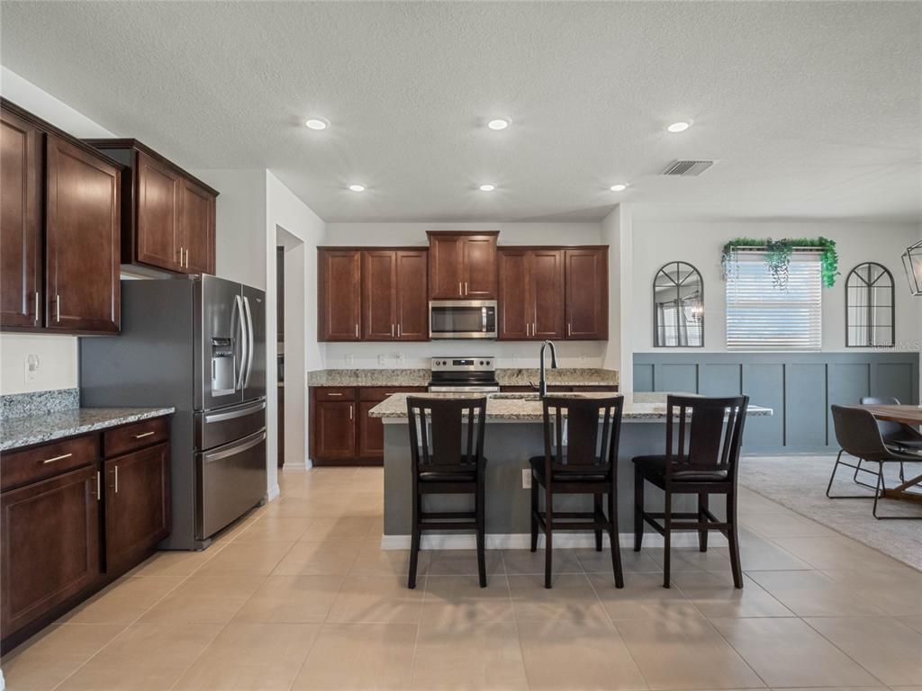 5021 Southwest 88th Street Ocala, FL 34476 - Photo 8 of 40 a kitchen with kitchen island granite countertop wooden cabinets a center island stainless steel appliances and a dining table view