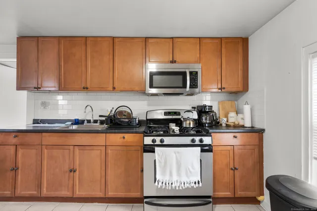 a kitchen with stainless steel appliances granite countertop a stove a sink and a microwave