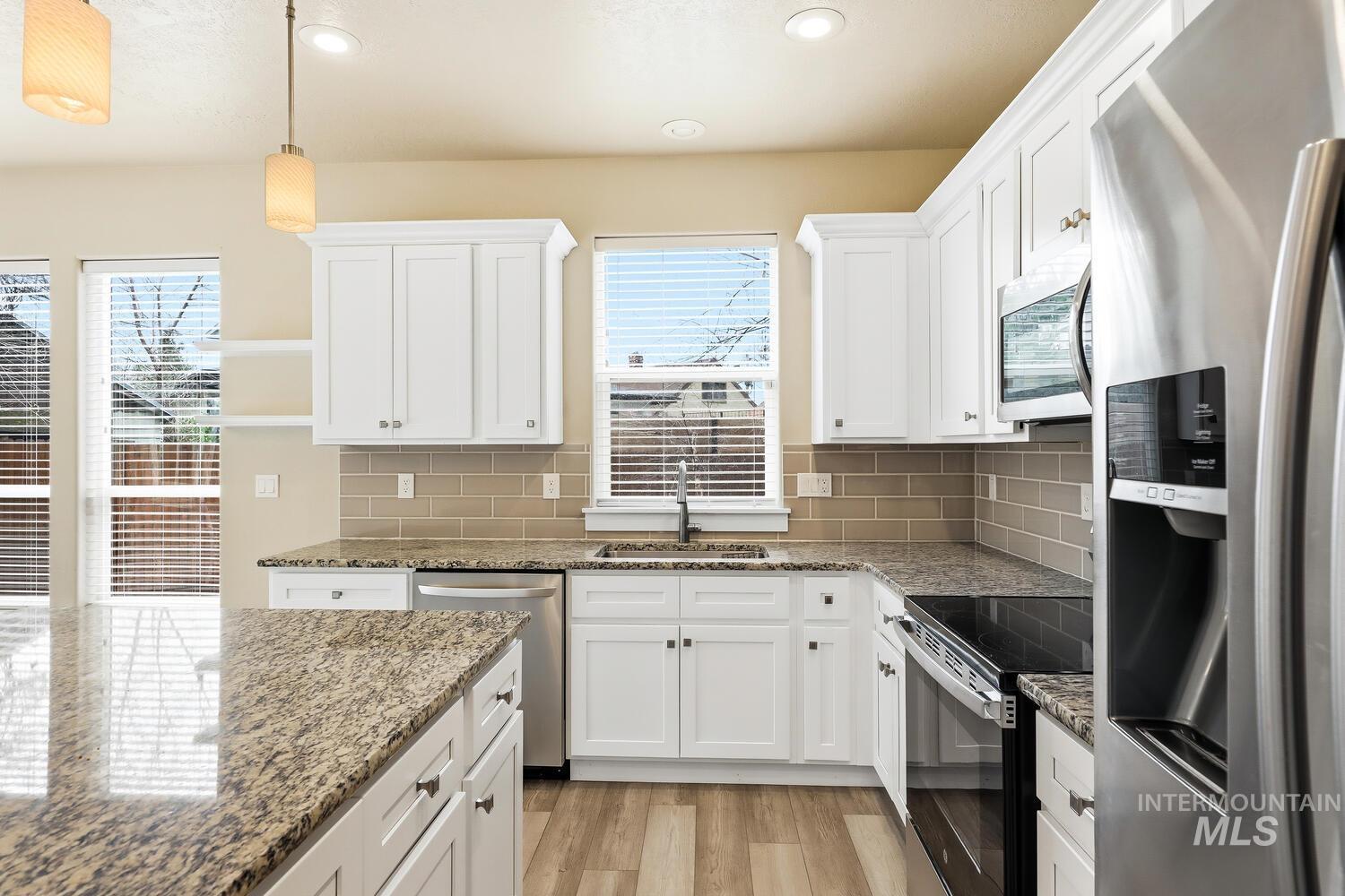 3003 West Moore Street Boise, ID 83702 - Photo 13 of 35 Kitchen with stainless steel appliances, white cabinets, light wood-style flooring, and healthy amount of natural light