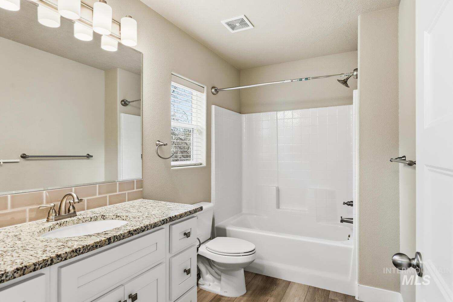 3003 West Moore Street Boise, ID 83702 - Photo 26 of 35 Bathroom with vanity, light wood-style floors, tub / shower combination, and tasteful backsplash
