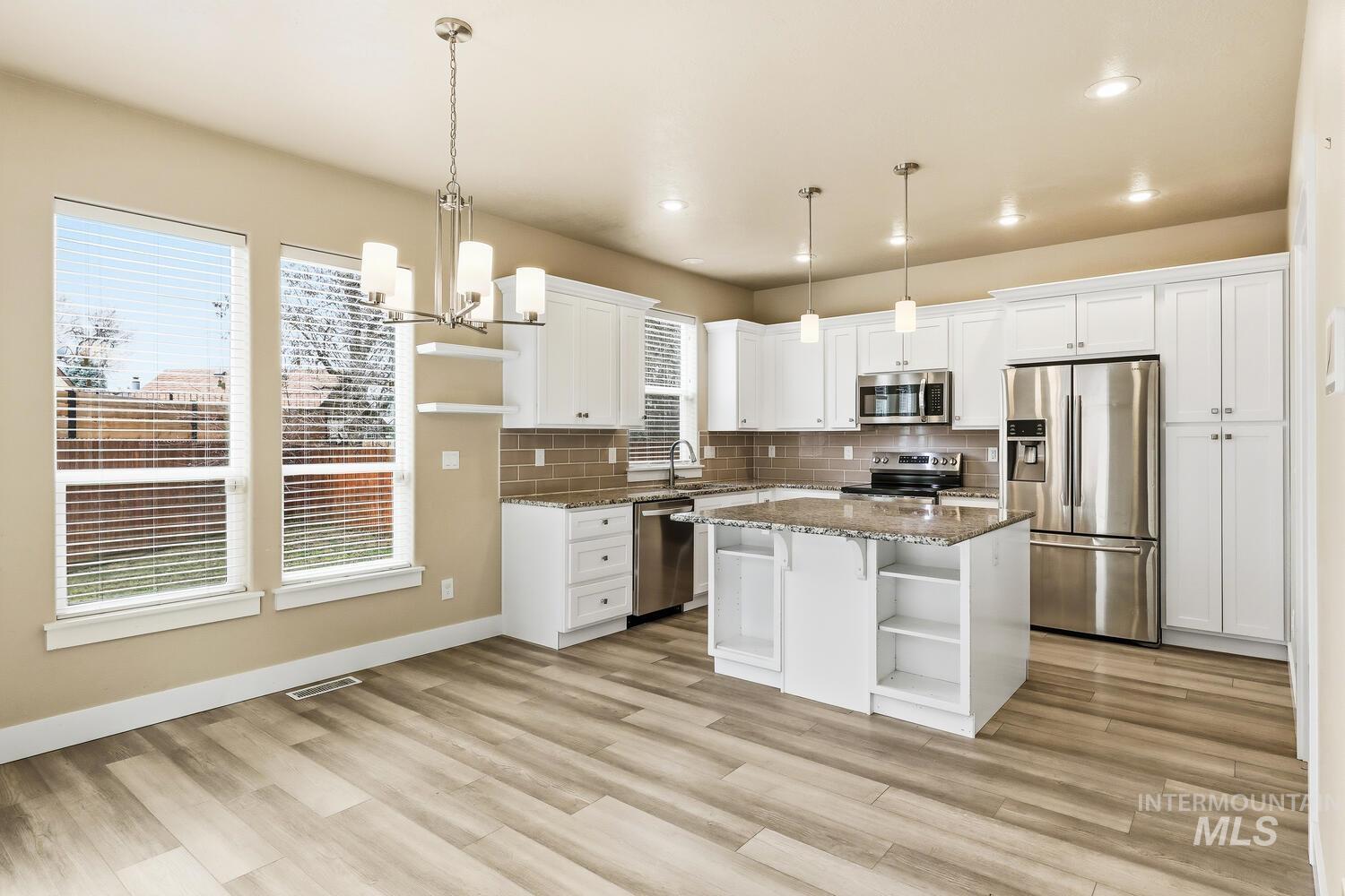 3003 West Moore Street Boise, ID 83702 - Photo 10 of 35 Kitchen with stainless steel appliances, dark stone countertops, tasteful backsplash, and white cabinets