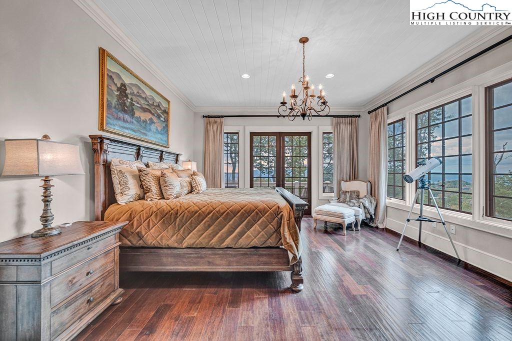 906 Fox Meadow Road Banner Elk, NC 28604 - Photo 16 of 40 a spacious bedroom with a large bed and a chandelier