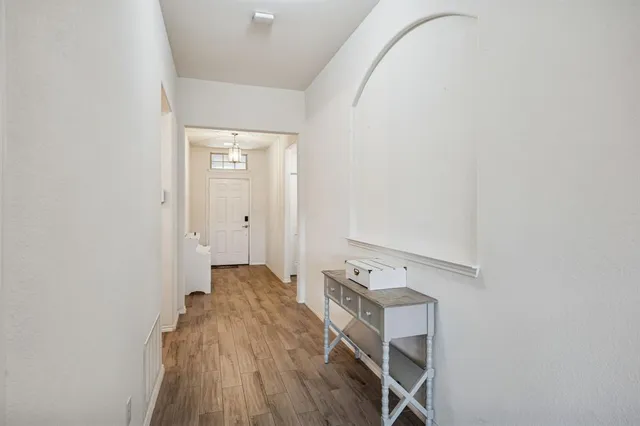 a view of a hallway with wooden floor and a bathroom