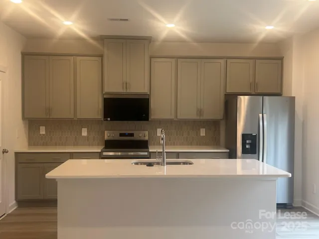 a kitchen with kitchen island a sink a stove and a refrigerator