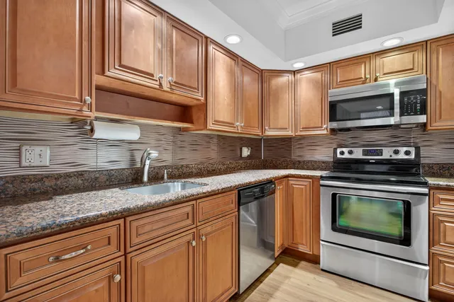 a kitchen with stainless steel appliances granite countertop a sink stove and microwave